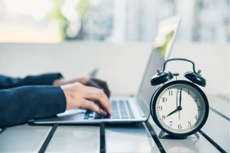 Clock shown in front of person working on computer