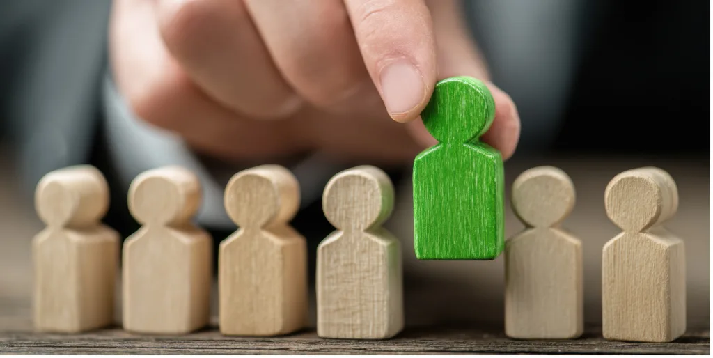 A hand picks up a green figurine from a number of others.